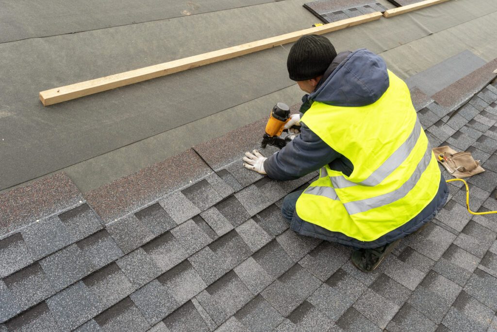 Roofer installing new asphalt shingles on a residential roof