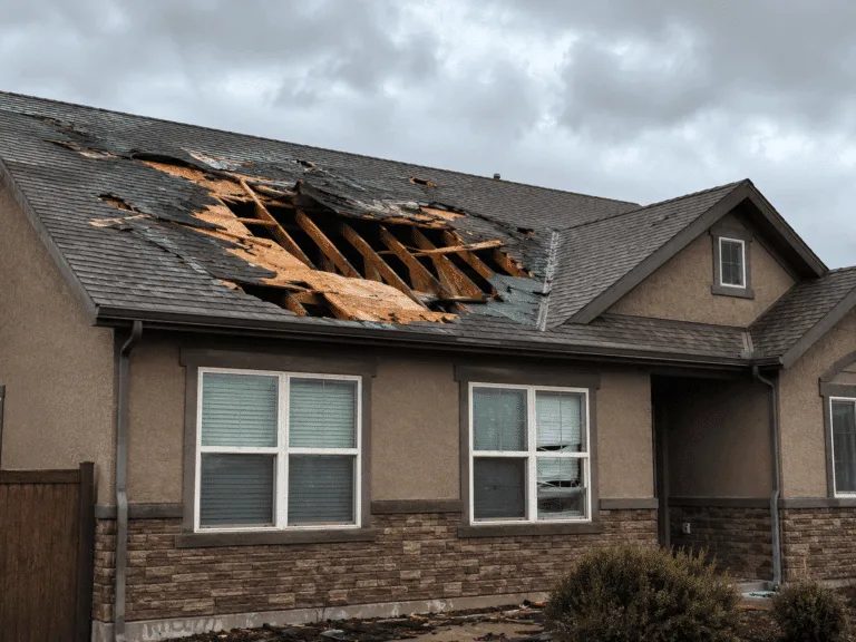 Home with severe storm damage torn across its shingle roof